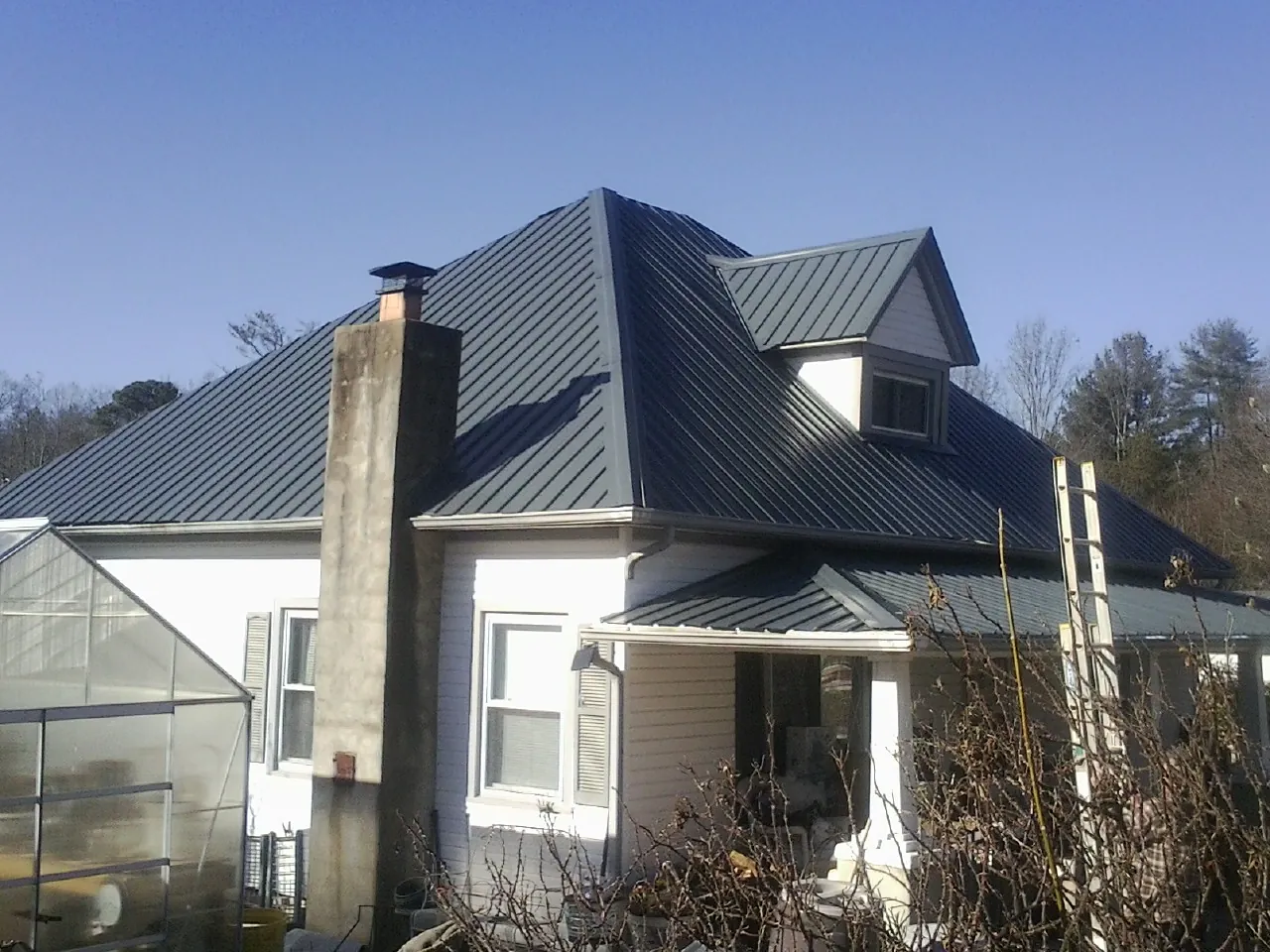 Dark blue standing seam metal roof on a white farmhouse with dormer — Slate & Tile Roof Repair by Roofing Brothers in Umpqua