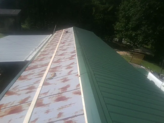Old rusted panels beside newly installed green metal roofing — Wind Damage Roof Repair by Roofing Brothers in Umpqua