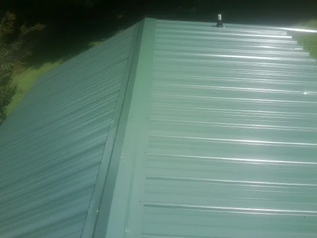 New green metal panels meeting at the ridge of a roof — Flat Roof Repair work by our crew in Umpqua