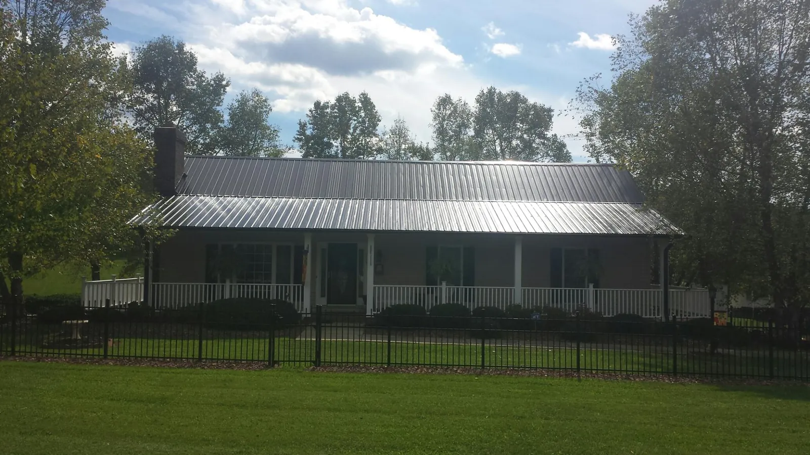 Gray metal roof on a brick ranch with a full width front porch — Gutter Guard Installation work by our crew in Umpqua