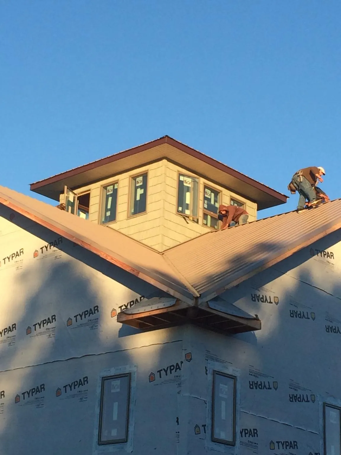 Roofers working around a rooftop cupola on a new metal roof at sunset — Roof Waterproofing in Umpqua by Roofing Brothers